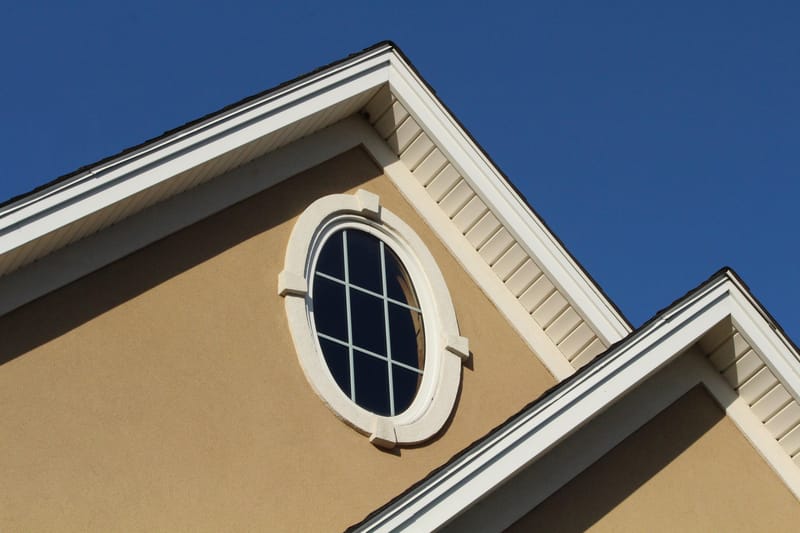 Gable and oval window of a stucco home exterior